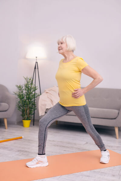 Blijf actief thuis - oudere vrouw doet oefeningen in huiskamer