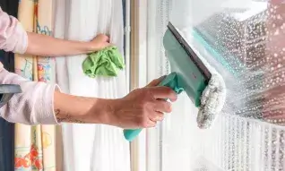 Huishoudelijke hulp is het raam aan het wassen