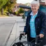 hulpmiddelen regelen - senior vrouw staat met rollator bij bushalte