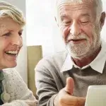 Woning aanpassen - Senior man en vrouw kijken tevreden naar tablet
