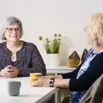 Ledenadviseur in gesprek met twee dames bij een kopje koffie