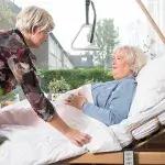 Vrouw verzorgt zieke bedlegerige oudere vrouw