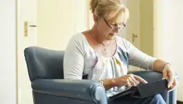 ontspanning - middelbare dame zit binnen op stoel met tablet