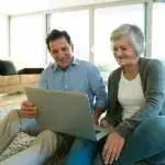 Dementie - ouder echtpaar zit op vloer en kijkt op laptop