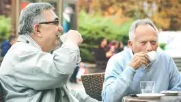 contact met anderen - twee senior mannen drinken kop koffie op terras restaurant