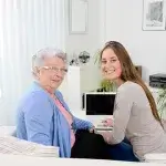 Oudere vrouw en jonge vrouw kijken op van laptop