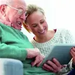 Oudere man op de bank en vrouw met tablet