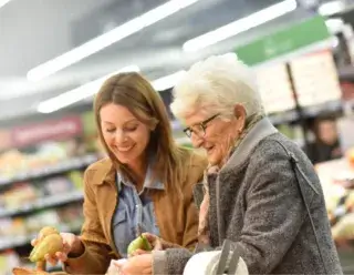 Vervangende mantelzorg - Oudere en jongere vrouw zoeken fruit uit in de supermarkt