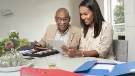 financiële administratie - oudere man en jonge vrouw aan tafel met administratie