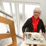 Verlof mantelzorger - Vrouw met ontbijtdienblad op de trap