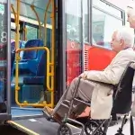 soorten hulpmiddelen - senior man in rolstoel wordt in de bus geholpen door zijn vrouw