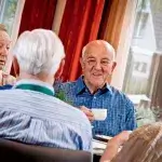 Vier oudere mannen gezellig samen aan tafel in een buurthuis