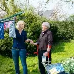 Vrouw met oudere man bij droogrek in tuin