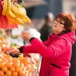 Middelbare vrouw koopt fruit op markt