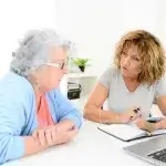 Vrouw helpt oudere vrouw bij administratie