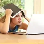Jonge vrouw kijkt wanhopig naar haar laptop
