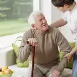 Verpleegkundige helpt oude man bij opstaan