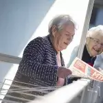 twee oudere dames praten met elkaar vanaf hun balkon