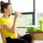 Jonge vrouw drinkt fruitwater uit fles - kraanwater met vers fruit