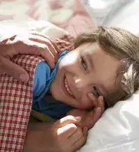 Plaswekkertraining - jongentje ligt lekker in bed en vader wenst welterusten