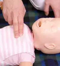 Detail van een babypop waar iemand tijdens de cursus EHBO bij baby's en kinderen reanimatie op oefent.