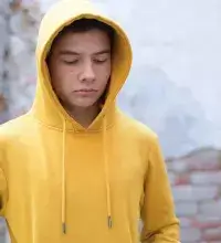 Zelfhulp depri - Jongen met gele hoodie kijkt somber