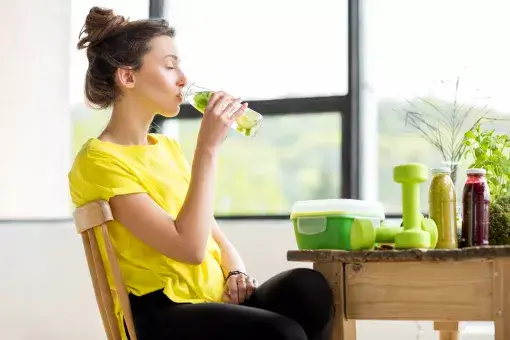 Jonge vrouw drinkt fruitwater uit fles - kraanwater met vers fruit