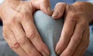 Artrose - twee handen pakken pijnlijke knie vast