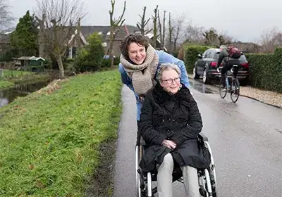 Oudere vrouw in rolstoel met begeleidster