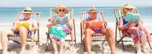 Vier senioren zitten op het strand in de stoel een boek te lezen